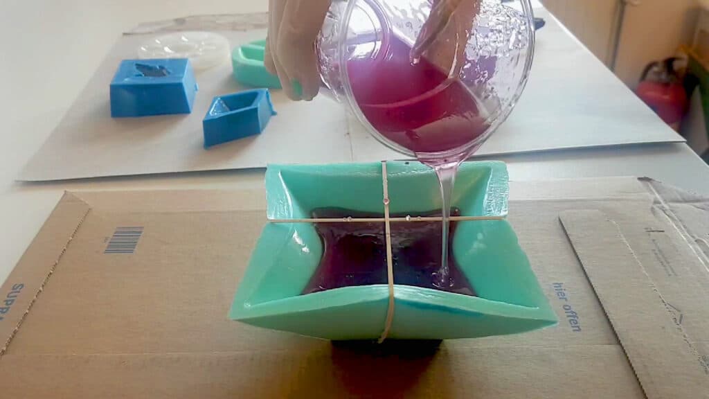 Pouring the resin mixture into the silicon mold (Image from <a href="https://www.youtube.com/watch?v=Mj06f8q3lNs" target="_blank" rel="noreferrer noopener">Pretzl Cosplay</a>)