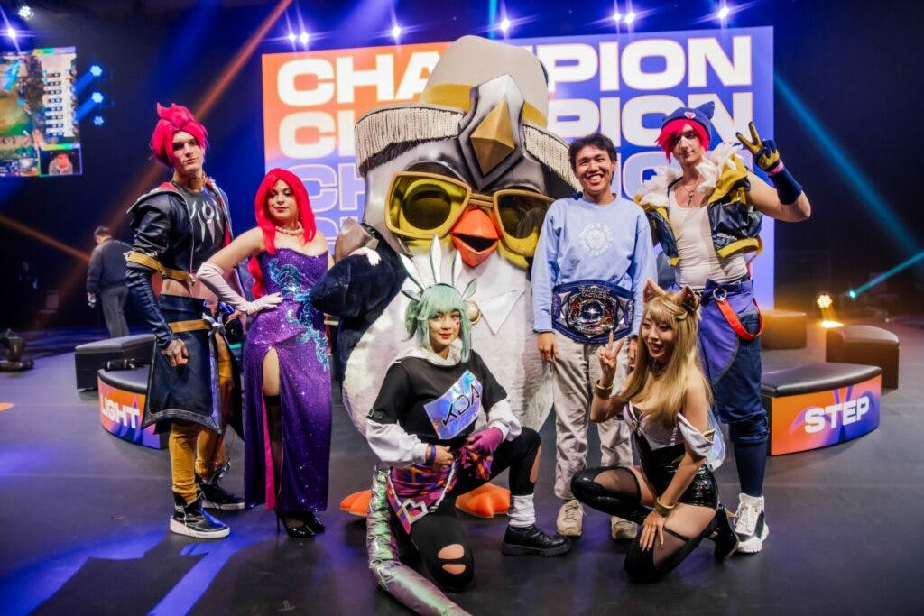 Milala with his TFT Vegas Open champion's belt alongside cosplayers and Pengu (Image via Riot Games)
